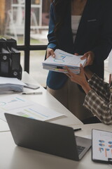 Group of confident business people point to graphs and charts to analyze market data, balance sheet, account, net profit to plan new sales strategies to increase production capacity.