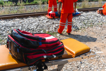 Close up backpack on emergency bed with injury man lying on stretcher near rail track background