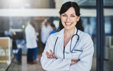Doctor, confidence and smile in hospital for healthcare, wellness or medical experience with stethoscope. Woman, portrait and pride in health facility with crossed arms for cardiology or medicine