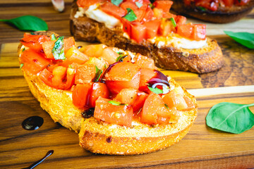 Italian Bruschetta served on a wooden plate, decorated with Basil.
