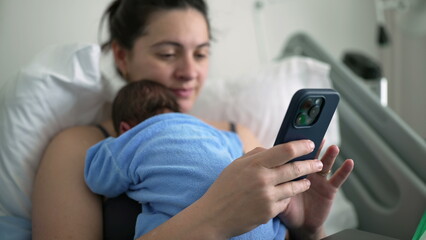New mother in hospital bed using smartphone with newborn baby on chest, multitasking between technology and parenting, postnatal care, family bonding, healthcare, remote communication