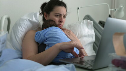 New mother multitasking in hospital bed with newborn baby, working on laptop, combining parenting...