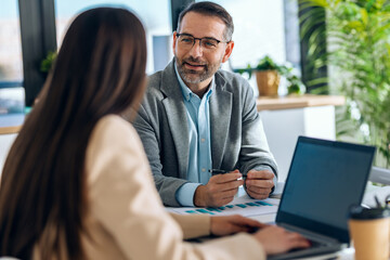 Elegant business people working together with laptop while talking in a modern office
