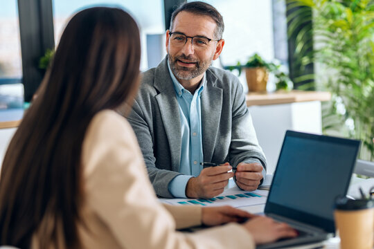 Elegant business people working together with laptop while talking in a modern office