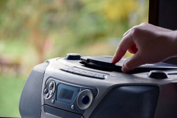 Homeowner is pushing the cd deck back into place with his fingers to play music from his favorite cd player unit, vintage concept, soft and selective focus.