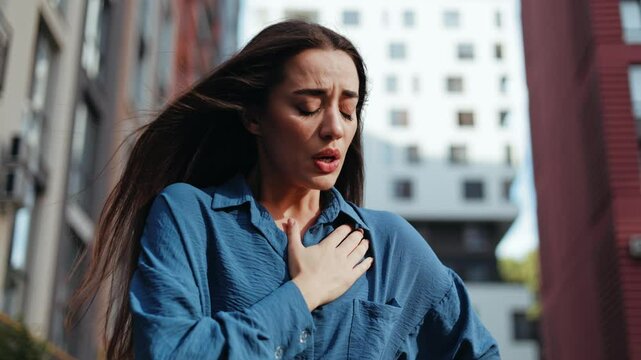 Stressed woman with anxiety or asthma attack outdoors. Health problems concept.