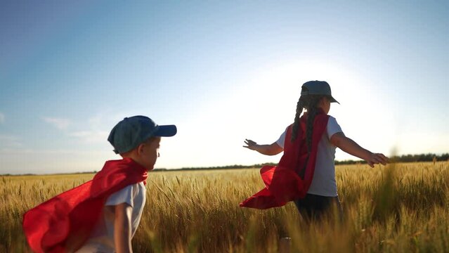 A group of kids playing a video game of superheroe together. Child hero fun concept. Superhero running sunset through the wheat with. children. A group of kids playing a game of running together.