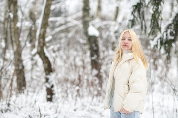 Portrait of a young beautiful blonde girl outdoors in winter in cloudy weather.