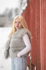 Portrait of a young beautiful blonde girl outdoors in winter in cloudy weather.