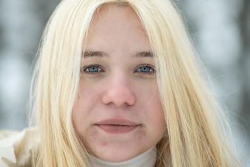 Portrait of a young beautiful blonde girl outdoors in winter in cloudy weather.