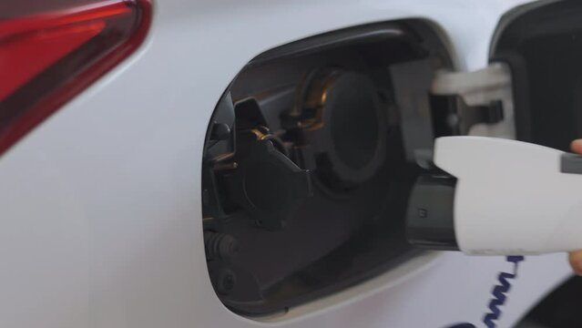 Close-up of hand plugging off charger from electric vehicle (EV), and ready to go. It shows sustainability, green technology, renewable energy, environmental conservation, and zero-emission vehicles. 