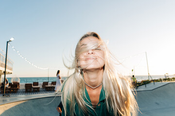 Wind in the hair. Lifestyle flash motion portrait of a cheerful  woman with long blond hair.