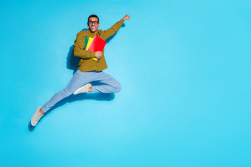 Full size photo of pretty young male flying superhero hold copybooks wear trendy plaid outfit isolated on blue color background © deagreez