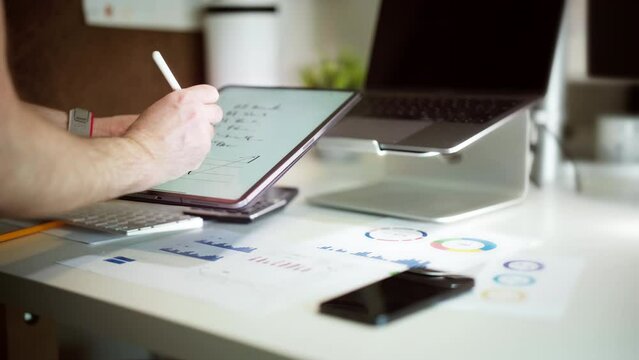 Marking checklist on tablet screen. Notes after project meeting. Office equipment.