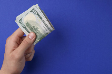 Money exchange. Man holding dollar banknotes on blue background, top view. Space for text