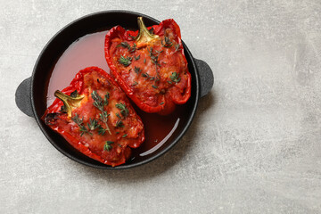 Tasty stuffed peppers in dish on light grey table, top view. Space for text
