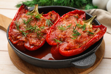 Tasty stuffed peppers in dish on white wooden table, closeup