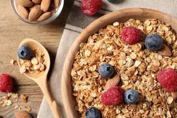 Tasty granola with fresh berries and nuts on wooden table, flat lay