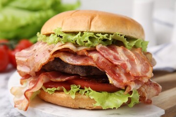 Delicious burger with bacon, patty and tomato on table