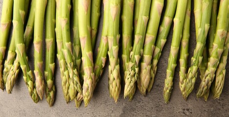 Fresh green asparagus stems on grey textured table, flat lay