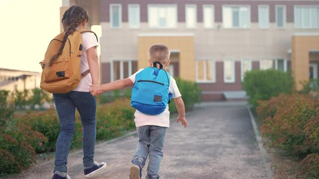 A group of children running around in backpacks at school. Backpack happy boy concept. Kids are back to school. A group of children running back to school with backpacks lifestyle.