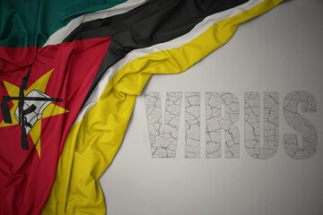 waving colorful national flag of mozambique on a gray background with text virus .