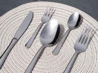 Minimalist silverware: close-up of a knife, forks, and spoons on a round placemat