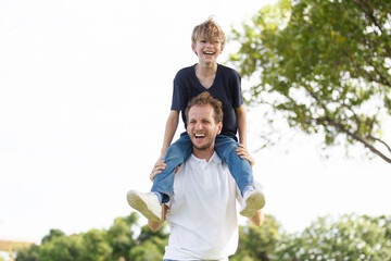 Fototapeta premium Man piggyback his son on a shoulder and walking around the park.