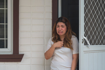 An Asian woman in her 30s breaking down and crying, overwhelmed by unpaid bills and relationship issues.