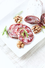 Sliced french salami with fresh rosemary on white background. Copy space.