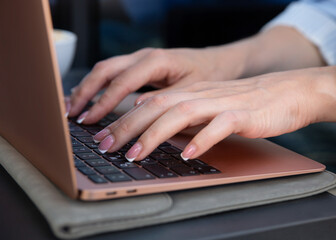 Close-up of businesswoman hands typing on laptop keyboard in cafe