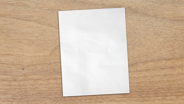 empty blank white grunge paper sheet placed on light oak wooden table counter, top view. sheet of blank note paper with blank space for design.