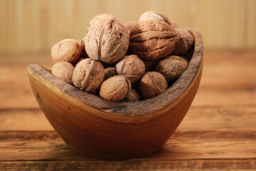 Walnuts in Wooden Bowl on a Brown Background. Whole Walnut on Rustic Table
