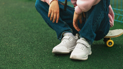 child skater, kid girl sitting relax at skatepark with skateboard. extreme sports in skate park