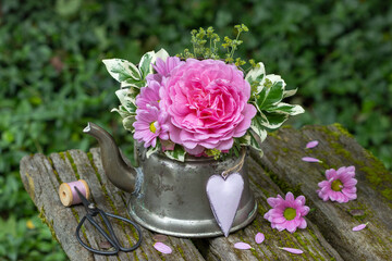 Blumen-Arrangement mit pink Rose Princess Alexandra of Kent, Chrysanthemen und Spindelstrauch-Zweigen im vintage Teekessel