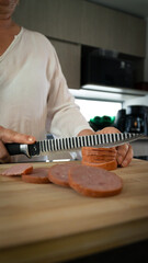 Vertical shot of a knife slicing sausage into slices.