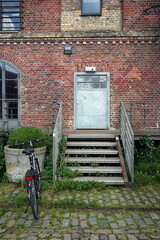 Graue Stahltür mit Graffiti mit Fluchttreppe aus Riffelblech am alten Kornspeicher mit Fassade aus...