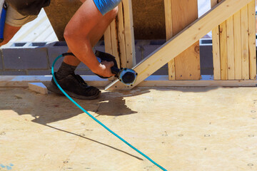 An air nail hammer is used by framing contractor to nail wooden beams
