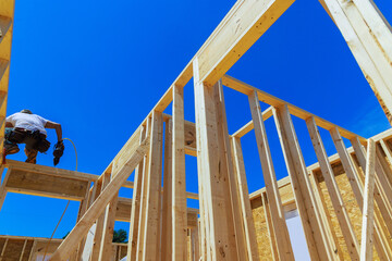Working with an air nail hammer, framing contractor nails wooden beam using pneumatic nail hammer
