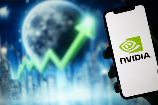 Porto, Portugal - April 30, 2024: In silhouette, a hand holds a mobile phone displaying the Nvidia logo. The background features a green stock market arrow pointing upward alongside a moon
