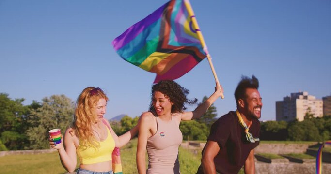 inclusive sexuality defenders friends have a fun time and laugh Celebrating LGBT Pride with Unity, transgender woman hold and rise a LGBT flag