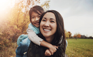 Obraz premium Portrait, asian family and piggy back in park, bonding together and vacation in Japan. Face, parent and girl with smile, outdoor and mother carrying kid, nature and holiday with game for fun and joy