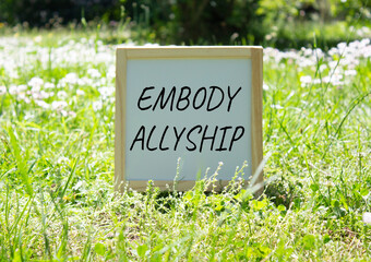 Embody Allyship symbol. Concept word Embody Allyship on white chalk background. Beautiful meadow background. Business and Embody Allyship concept. Copy space