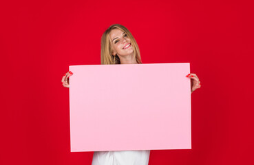 Smiling woman showing blank billboard with copy space for text. Banner sign board promo. Beautiful girl with empty advertising poster. Advertising of products and announcement of discounts and sales.