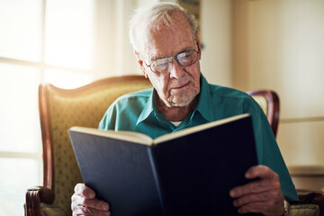 Elderly man, peace and reading book in home, literature and language for learning in retirement. Old person, fiction and textbook for knowledge to relax on sofa, glasses and studying information