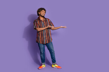 Full size photo of positive friendly man dressed print shirt arms presenting object empty space isolated on purple color background