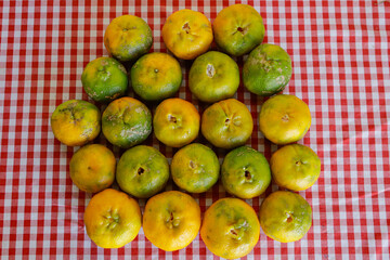 Organic tangerine (Citrus reticulata), on a red and white towel, with some stains. The fruit is also known as ponca, tangerine, morgote, bergamot or mimosa, a fruit with a strong