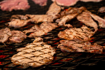 pork steaks in Grilling pork steaks over open flame, with charred grill marks, sizzling and ready to serve.