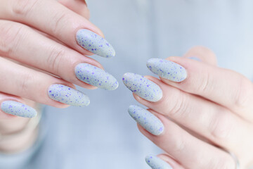 woman hands with long nails light gray blue manicure