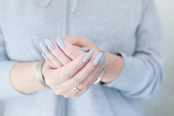 woman hands with long nails light gray blue manicure